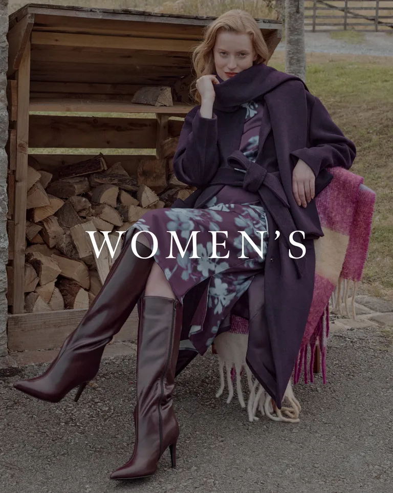 Women's fashion model in purple coat, floral dress, and knee-high boots
